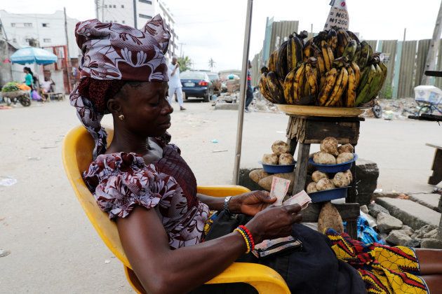 A woman selling plantain along a road counts the Nigerian naira near a currency exchange market in Ikeja district in Lagos, Nigeria August 12, 2017.