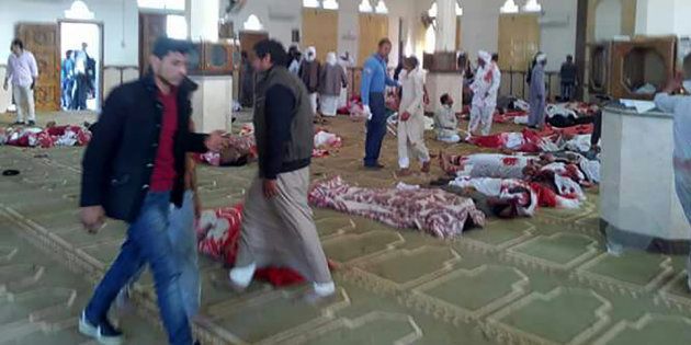 Egyptians walk past bodies following a gun and bombing attack at the Rawda mosque, roughly 40 kilometres west of the North Sinai capital of El-Arish, on November 24, 2017.