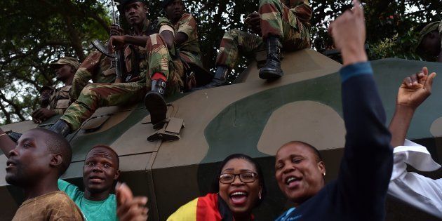 People celebrate next to soldiers in the streets of Harare, after the resignation of Zimbabwe's former president Robert Mugabe on November 21, 2017.