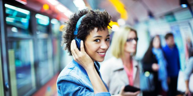 Smiling woman listening to headphones in subway