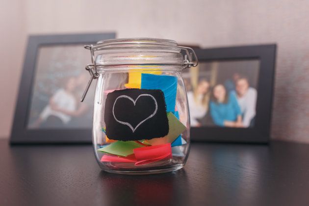 closed tin with stickers inside with a painted heart on the shelf with the paintings in the background