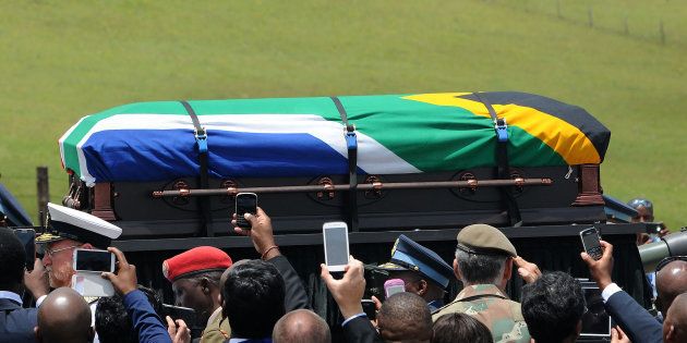 People take pictures as the coffin of South African former president Nelson Mandela is carried on a gun carrier for a traditional burial during his funeral in Qunu on December 15, 2013.