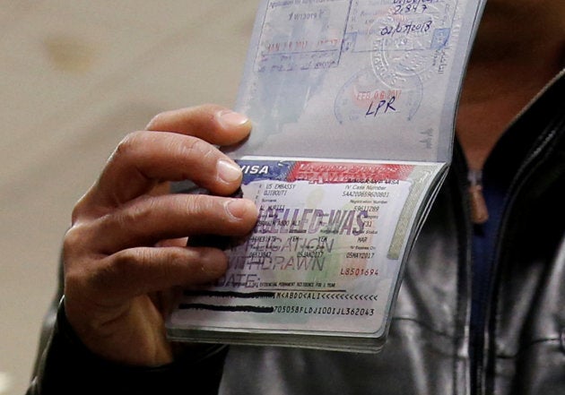 A member of the Al Murisi family, Yemeni nationals who were denied entry into the U.S. because of the travel ban, shows the cancelled visa in their passport from their failed entry to reporters as they successfully arrive to be reunited with their family at Washington Dulles International Airport in Chantilly, Virginia, U.S., February 6, 2017.