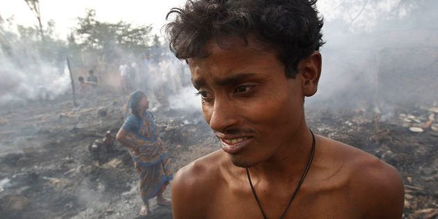 A boy and his mother stand next to their gutted hut after a fire in a slum area in New Delhi April 8, 2010.