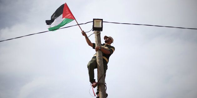 A man hangs a Palestinian flag from an electricity pole near the border with Israel in southern Gaza.