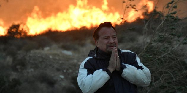 A man prays as the Creek fire advances behind him in the San Fernando Valley area of Los Angeles.