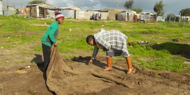 Funeka Sikhafungana and her eight-year-old son pick up a mat after law enforcement officials demolished their shack in Nkandla informal settlement in Bloekombos on Monday.