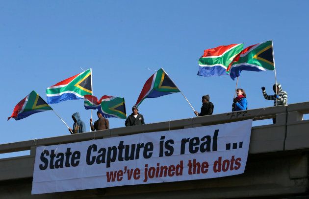 Protesters hang a banner as they hold flags in protest ahead of the African National Congress 5th National Policy Conference at the Nasrec Expo Centre in Soweto, South Africa, June 30, 2017.