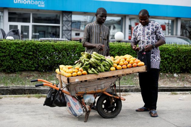 A man selling fruits in a wheelbarrow attends to a customer in front of a bank along a road in Ikoyi district in Nigeria's commercial capital Lagos April 20, 2018. REUTERS/Akintunde Akinleye