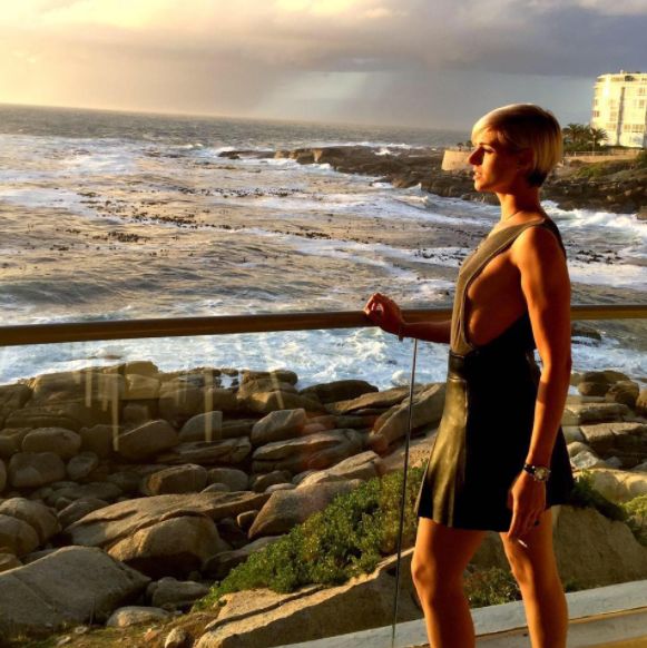 Berdine Odendaal smoking a cigarette on a balcony at sunset.