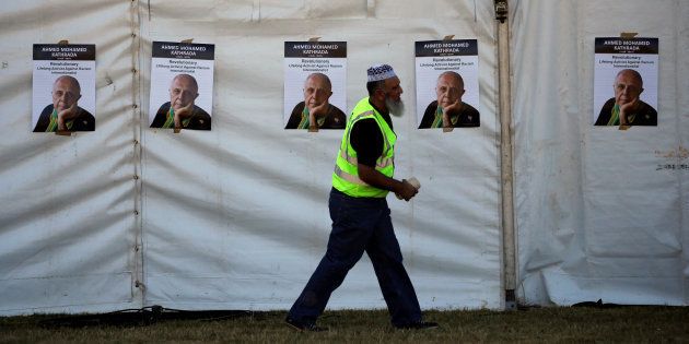 A worker walks past posters bearing the face of anti-apartheid activist Ahmed Kathrada, who was sentenced to life imprisonment alongside Nelson Mandela, ahead of his funeral at the Westpark Cemetery.