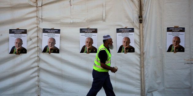 A worker walks past posters bearing the face of Veteran South African anti-apartheid activist Ahmed Kathrada, who was sentenced to life imprisonment alongside Nelson Mandela, ahead of his funeral at the Westpark Cemetery in Johannesburg, South Africa March 29, 2017. REUTERS/Siphiwe Sibeko