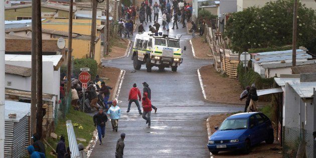 A South African Police armoured vehicle drives down a road dispersing protesters during clashes with police calling for the release of one of their colleagues, who was arrested for inciting violence, on July 13, 2018, in Hemanus.