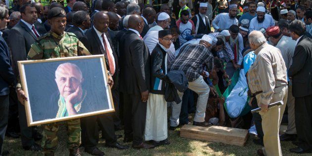 Helpers place the body of late South African anti-apartheid activist Ahmed Kathrada in the grave as South African ruling party African National Congress (ANC) leadership, political opposition leaders, dignitaries and family members attend the funeral at the Westpark Cemetery in Johannesburg, South Africa, on March 29, 2017.The funeral of celebrated South African anti-apartheid activist Kathrada was transformed into a rally against President Jacob Zuma, who did not attend after the family of the ANC stalwart, one of Nelson Mandela's closest colleagues in the struggle against white minority rule who died on March 28, 2017 aged 87, had asked Zuma to stay away.