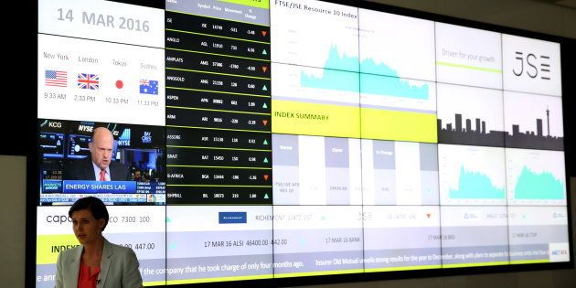 A television presenter speaks in front of a reception with an electronic board displaying movements in major indices at the Johannesburg Stock Exchange building in Sandton Johannesburg, March 14, 2016.