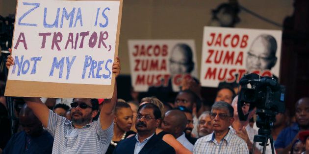 Protesters raise placards against South African President Jacob Zuma in Johannesburg, Saturday, April 1, 2017, during a memorial service for anti-apartheid stalwart Ahmed Kathrada, who died Tuesday. The memorial service for Kathrada turned into a protest against South African President Zuma. (AP Photo/Denis Farrell)