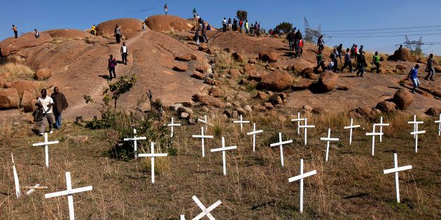 Members of the mining community walk near crosses placed at a hill known as the