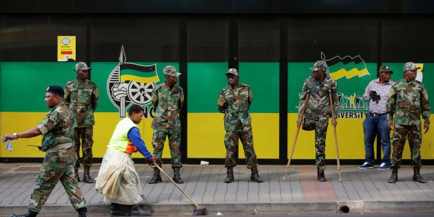 A worker sweeps the street as members of the Umkhonto We Sizwe Military Veterans Association (MKMVA) stand guard at the ANC headquarters in downtown Johannesburg, South Africa, September 5, 2016. REUTERS/Siphiwe Sibeko