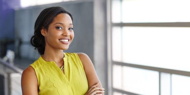 Friendly african american woman standing with arms crossed in a modern bright office