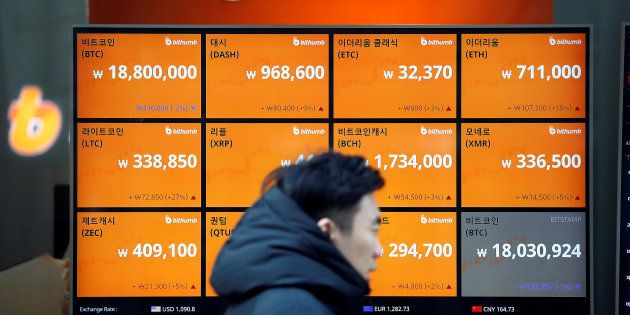 A man walks past an electric board showing exchange rates of various cryptocurrencies including Bitcoin (top L) at a cryptocurrencies exchange in Seoul, South Korea December 13, 2017.