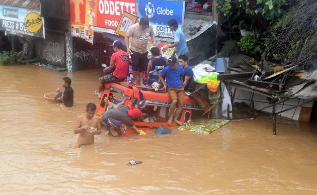 Residents are seen on the top of a partially submerged vehicle along a flooded road in Cagayan de Oro city in the Philippines, December 22, 2017.