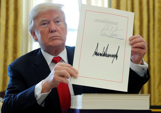 U.S. President Donald Trump displays his signature after signing the $1.5 trillion tax overhaul plan in the Oval Office. Dec. 22, 2017.