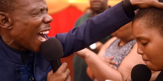 KATLEHONG, SOUTH AFRICA JANUARY 29: (SOUTH AFRICA OUT): Prophet Paseka Mboro Motsoeneng prays for Relebogile Ndlovu and her family during a special service at the Incredible Happenings Ministries Church on January 29, 2017 in Katlehong, South Africa. The Ndlovu family opted for the help of Motsoeneng Pastor Mboro as he is affectionately known, after they couldnt get medical healing for the ailing 18-year-old daughter. (Photo by Lucky Nxumalo/Foto24/Gallo Images/Getty Images)