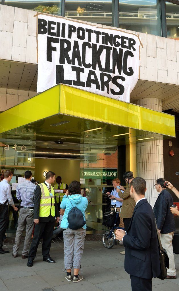 A group of commuters stand and take pictures of anti-fracking demonstrators, as they sit with their hands super-glued to each other at the offices of Bell Pottinger in High Holborn in central London, the PR company used by energy company Cuadrilla.
