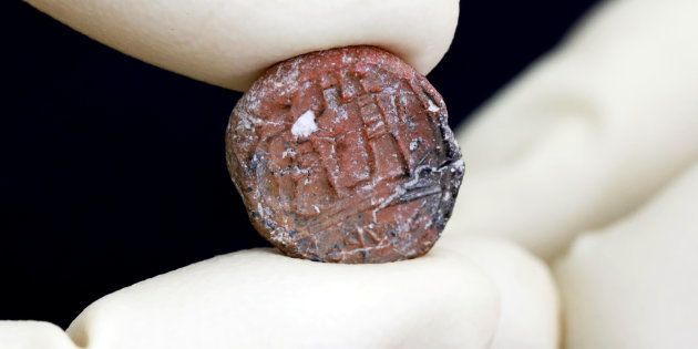 A conservator shows a 2,700-year-old clay seal impression which archaeologists from the Israel Antiquities Authority say belonged to a biblical governor of Jerusalem and was unearthed in excavations in the Western Wall plaza in Jerusalem's Old City January 1, 2018. REUTERS/Nir Elias