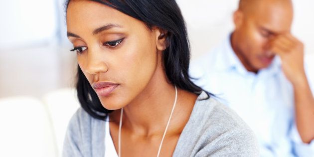 Closeup of sad young woman in living room with man after an argument