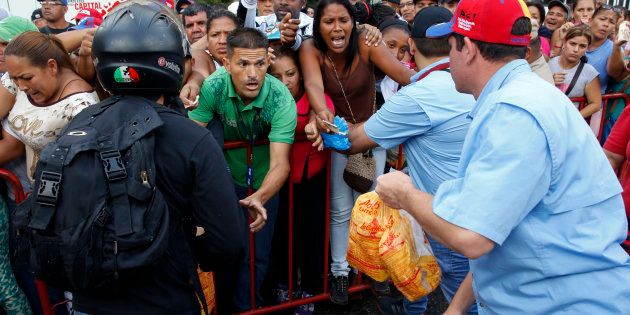 People attempt to buy chickens at a Mega-Mercal, a subsidized state-run street market, in Caracas January 24, 2015. President Nicolas Maduro shook up complex currency controls on Wednesday and also prepared Venezuelans for a rise in the world's cheapest fuel prices in response to a recession worsened by plunging oil revenue. The socialist-run OPEC member's economy shrank 2.8 percent in 2014 while inflation topped 64 percent, the socialist leader announced in a speech to parliament, in what is almost certainly the worst performance in Latin America. REUTERS/Carlos Garcia Rawlins (VENEZUELA - Tags: BUSINESS POLITICS FOOD SOCIETY)