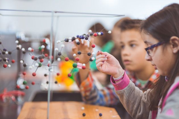 Group of elementary students doing STEM activities in a classroom looking a molecule example