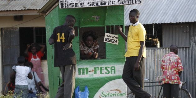 Residents perform at a mobile phone transaction at a stall within the trading centre of the village of Nyang'oma Kogelo, west of Kenya's capital Nairobi, July 15, 2015.