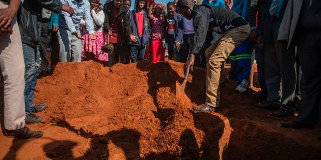 A man covers with ground the hole for the coffin of the young 16 year old Moswi Matlhomala Moshoeu in Coligny.