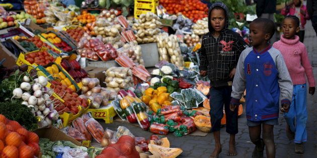 Children walk past a vegetable stall in Soweto July 23, 2015.