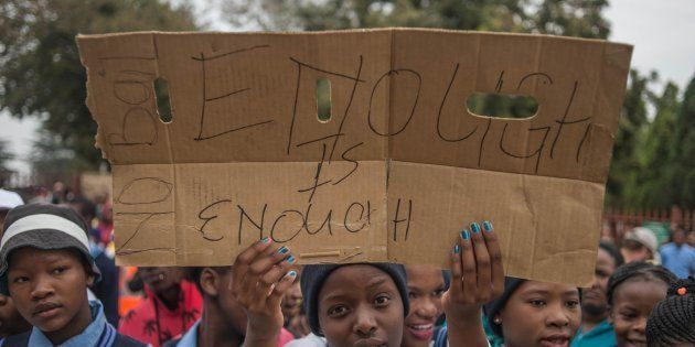Residents from the Scotland informal settlement in Coligny hold a sign reading 'No bail, enough is enough' during a protest outside the Coligny Magistrate court on May 8, 2017.