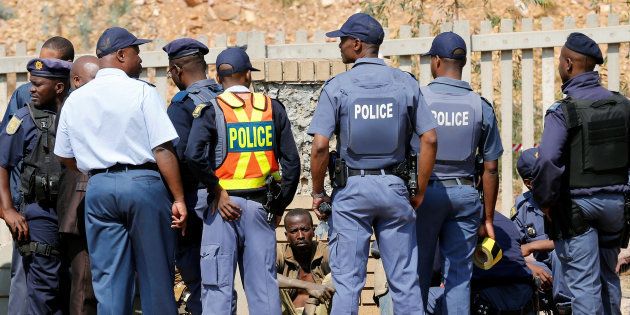 A suspected illegal miner (C) is questioned by police after he emerged from Johannesburg's oldest gold mine in Langlaagte, South Africa. September 12, 2016.