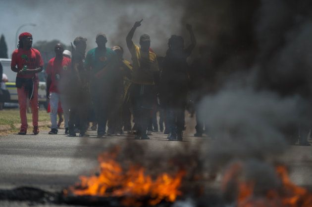 Protesters, including disgruntled parents, EFF and ANC supporters march near burning tyres during clashes with South African riot police officers during unrest over language and admission policies at Ho'rskool (Hoerskool) Overvaal school on January 17, 2017 in Vereeniging, South Africa.