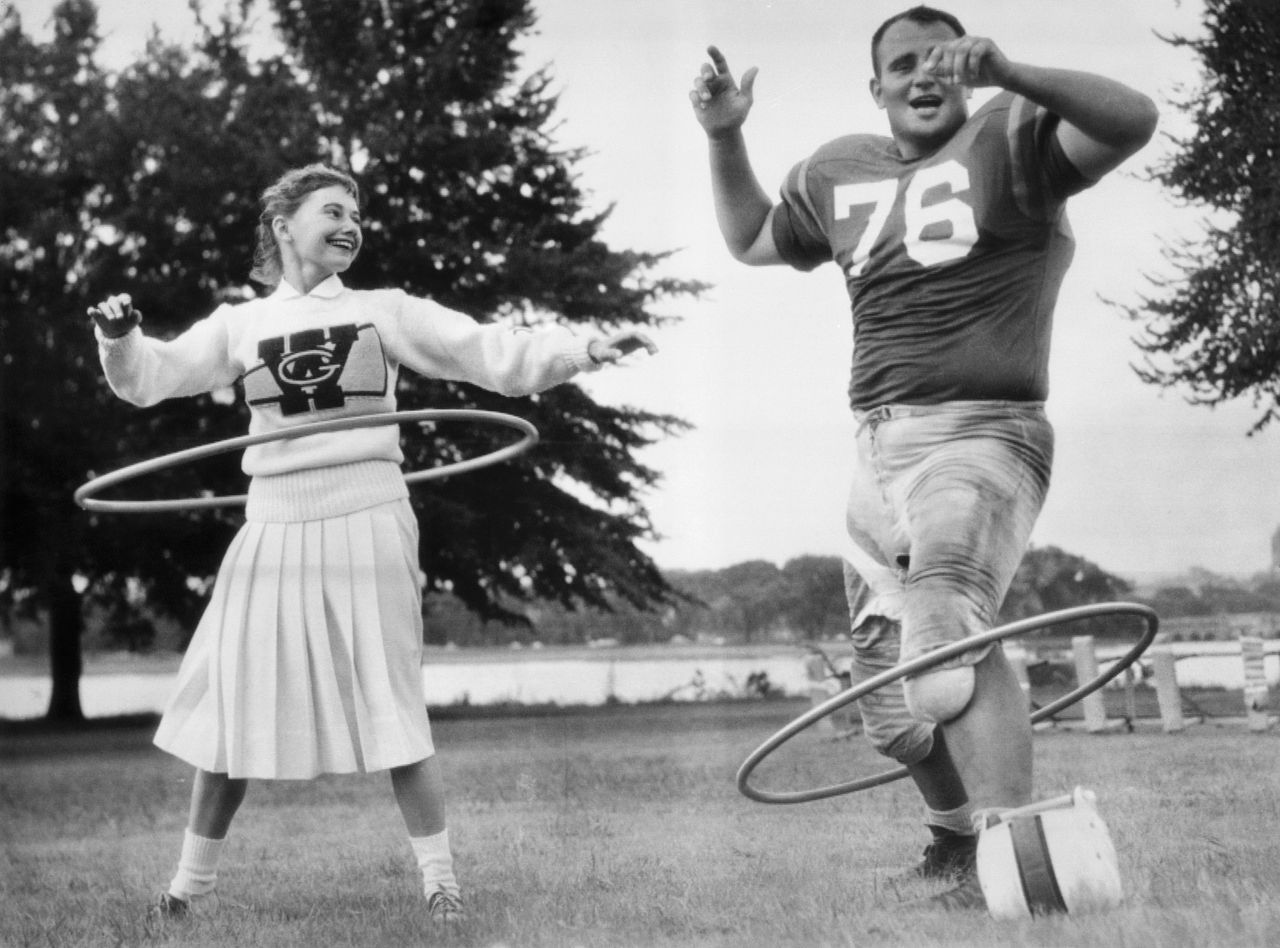 George Washington University cheerleader Anne Sneeringer unsuccessfully attempts to coach Ed Rurbach in the art of spinning a toy hoop, circa 1958.