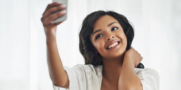 Shot of a beautiful young woman taking a selfie while relaxing in her bedroom