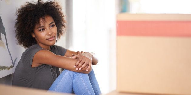 Shot of an attractive young woman feeling nostalgic while sitting amongst packed boxes