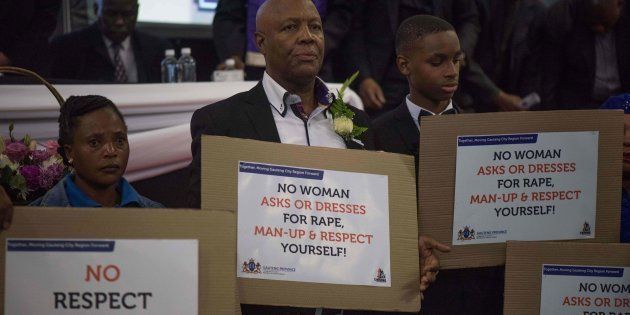 South African men hold placards denouncing violence against women during the memorial service for Karabo Mokoena.