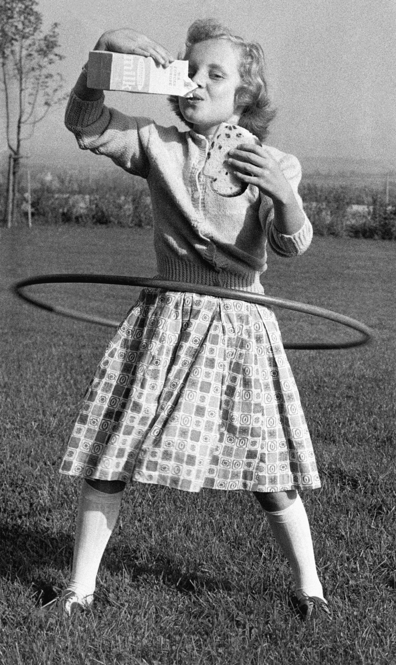 Mimi Jordan, 10, drinks milk and holds a sandwich while hooping.