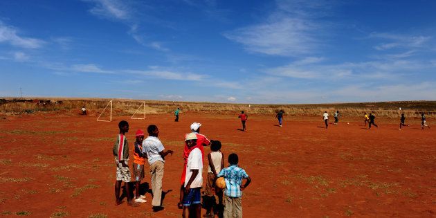 Children watch others enjoying a game of football on June 15, 2009 in Mogale City, South Africa.