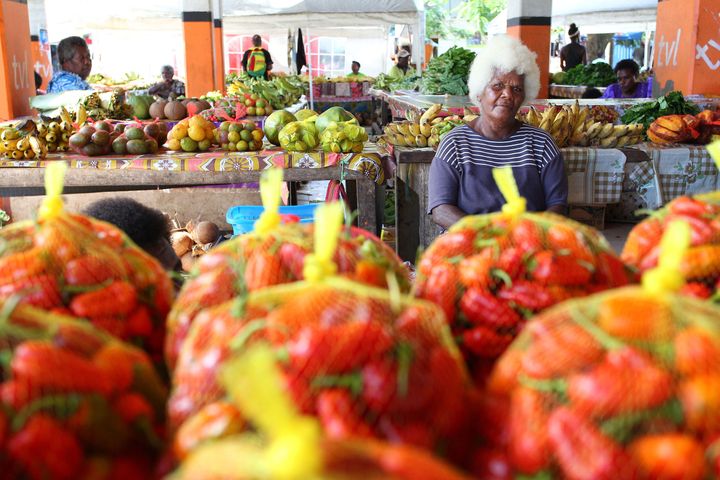 市場で野菜や果物をプラスチックネットで売っている女性