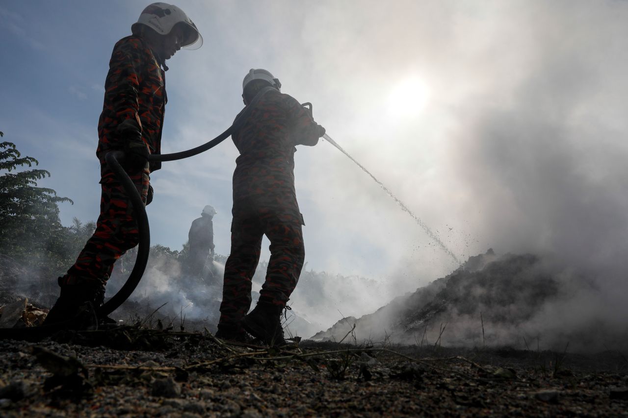 Firemen put out a blaze at a dumpsite on a palm oil plantation near Jenjarom, Feb. 2. Plastic fires are notoriously difficult to extinguish.