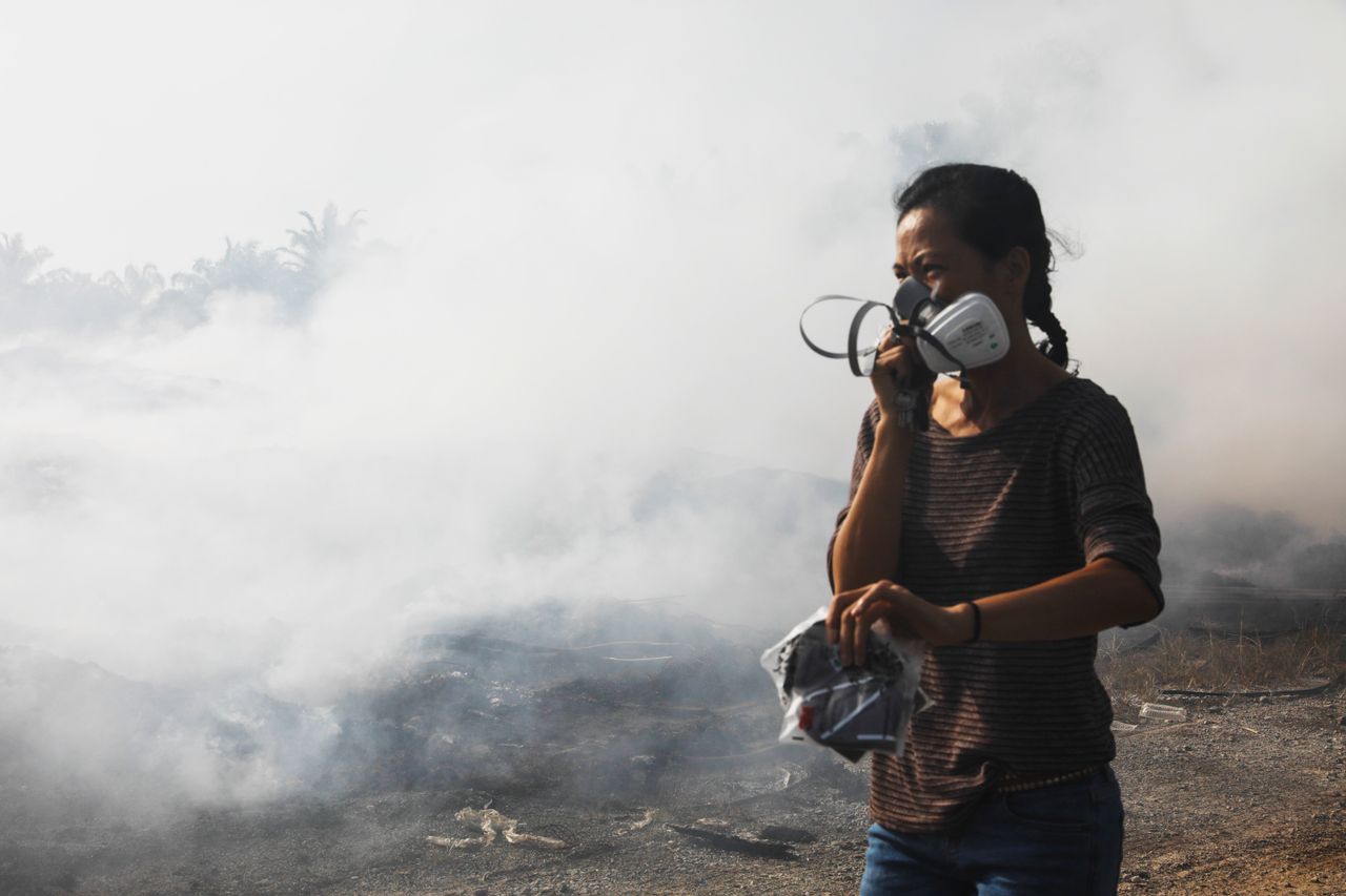 Pua walks past a burning site at a palm oil plantation near Jenjarom, Feb. 2. Activists blame widespread burning of plastics for residents’ increasing complaints of headaches, respiratory problems, skin allergies and other ailments.