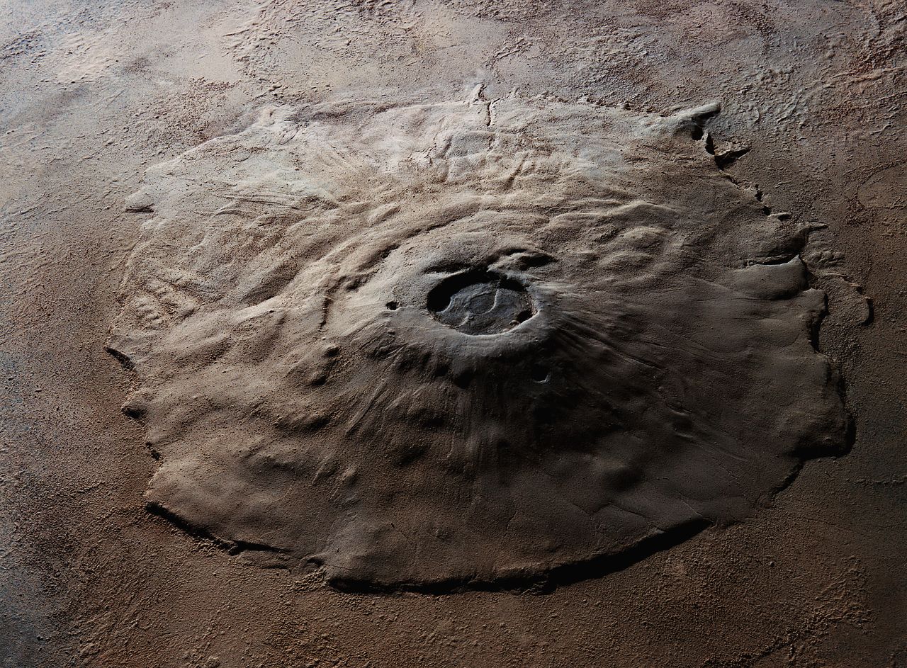 Orbital view of the Olympus Mons volcano on Mars, the largest known volcano in the solar system. It measures 375 miles across at its base, and the walls of the volcano tower 15 miles above the plains of Mars.