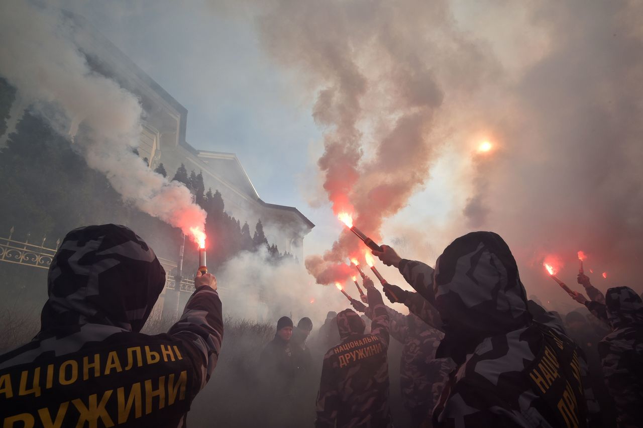 Activists and supporters of the Ukrainian far-right party National Corps burn flares in front of the private house which supposedly belongs to Svynarchuk in Kiev region on March 3, 2019.