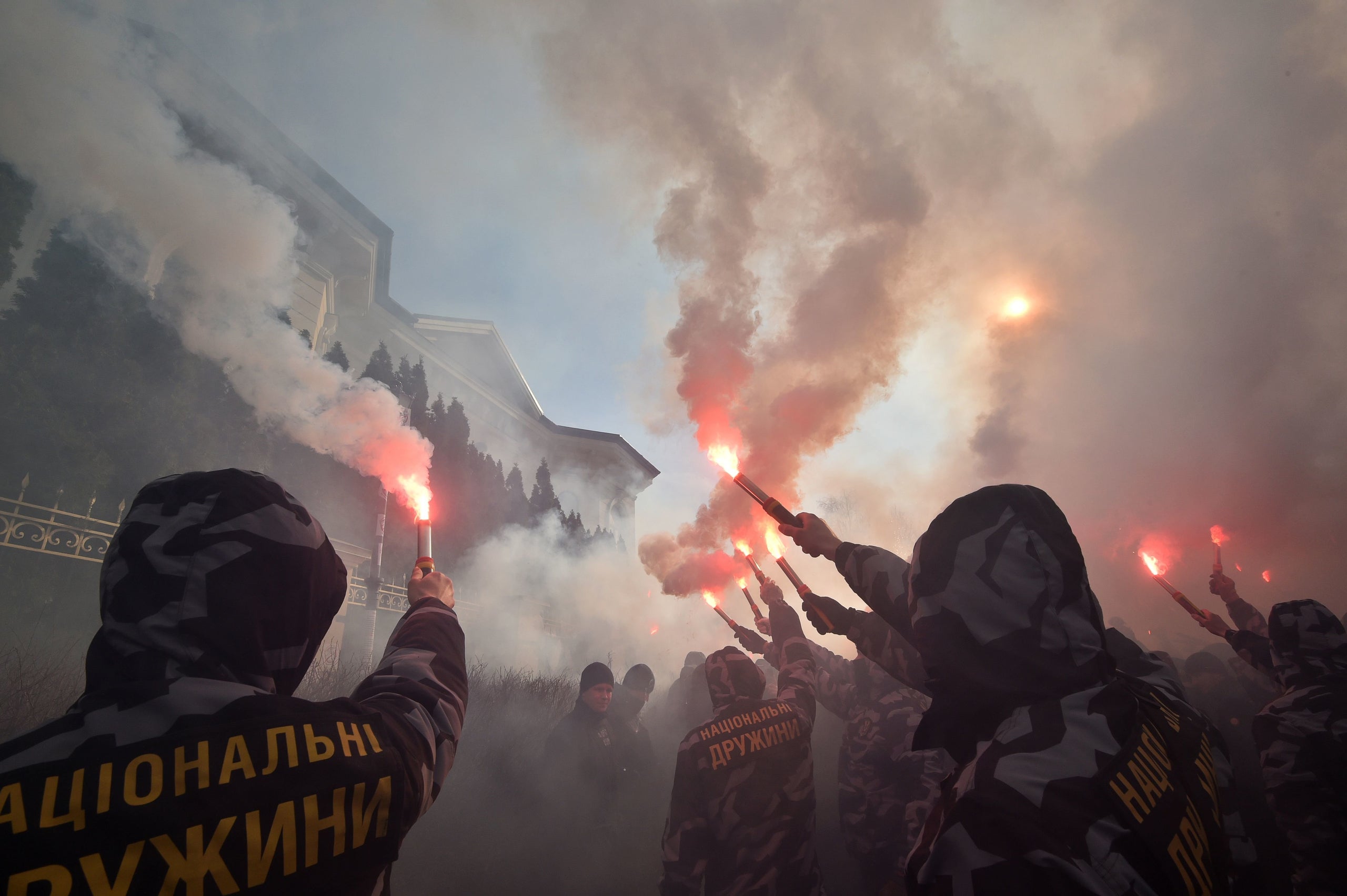 Activists and supporters of the Ukrainian far-right party National Corps burn flares in front of the private house which supp